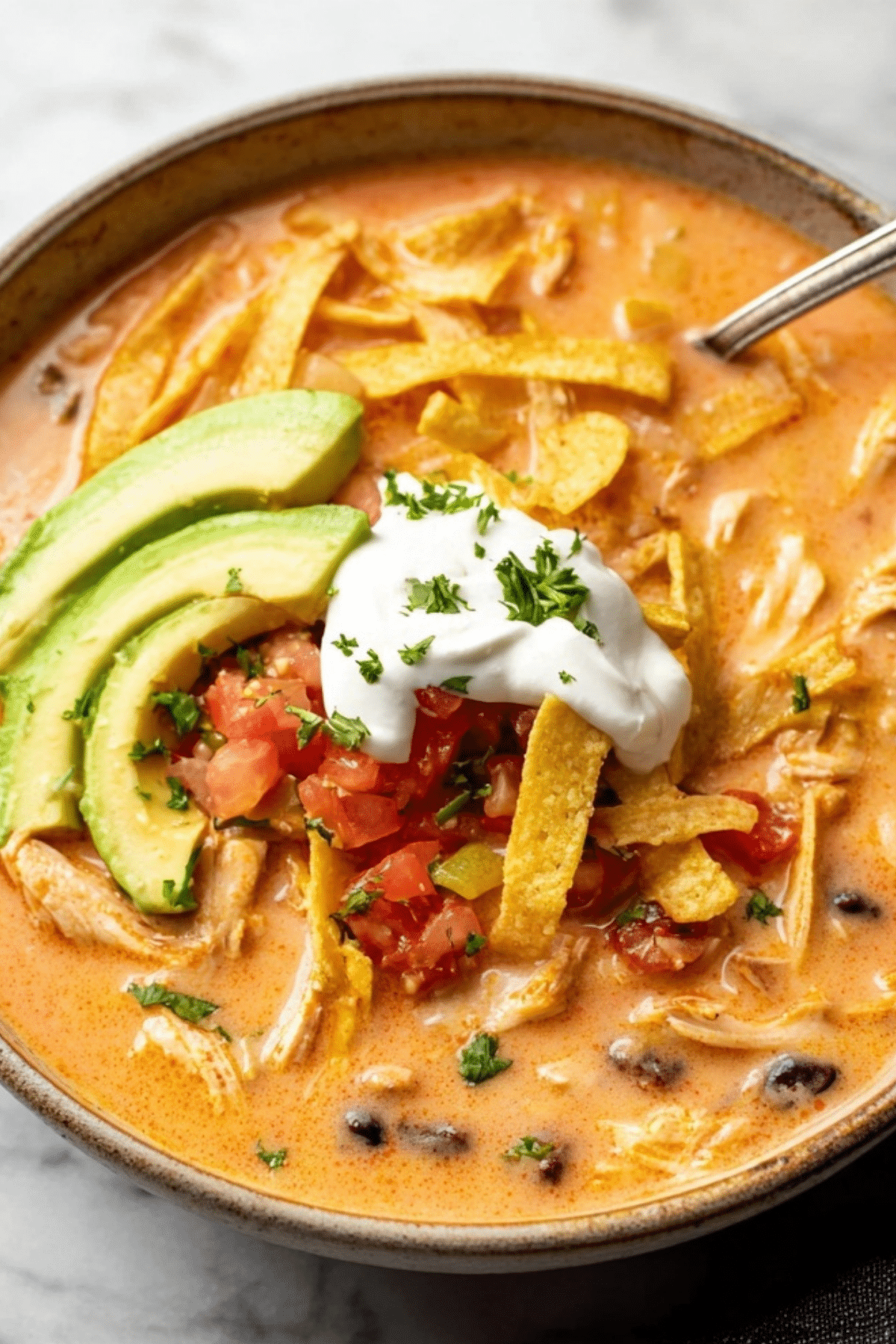 creamy chicken tortilla soup served with toppings like avocado and tortilla strips