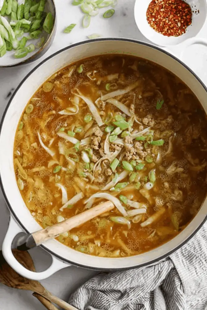 Egg roll soup in a bowl with cabbage, pork, and green onions.