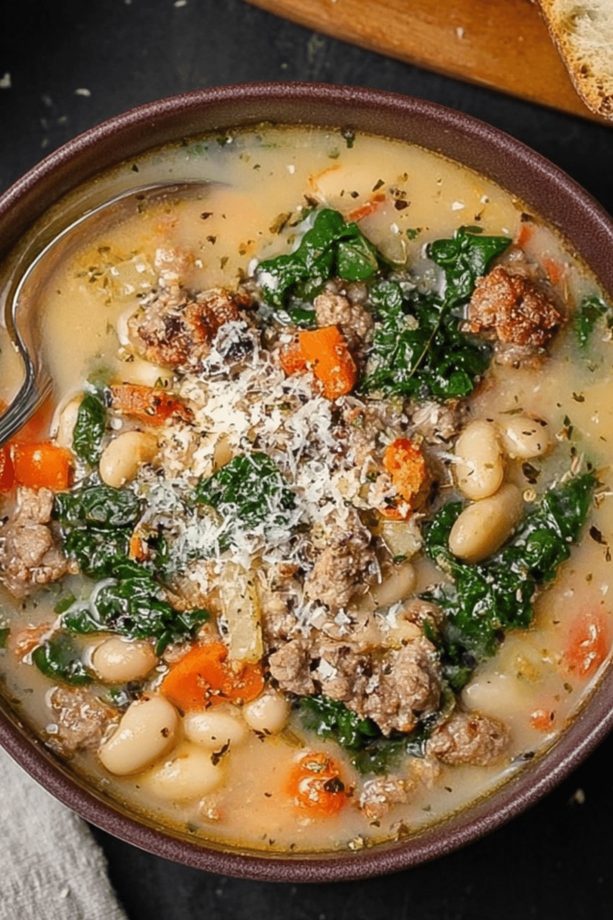 Italian Sausage and White Bean Soup served in a bowl with fresh herbs and Parmesan cheese