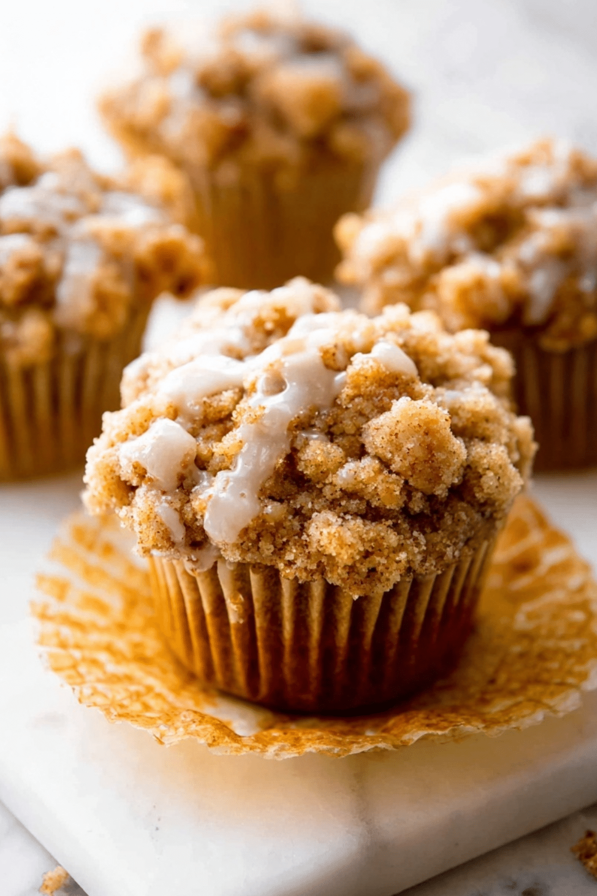 Pumpkin Crumb Cake Muffins topped with a pumpkin spice crumble and maple icing