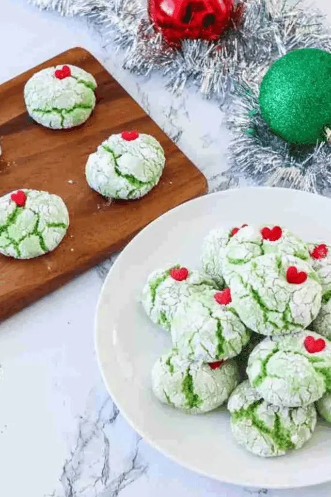 Grinch cookie recipe featuring green crinkle cookies with red heart sprinkles