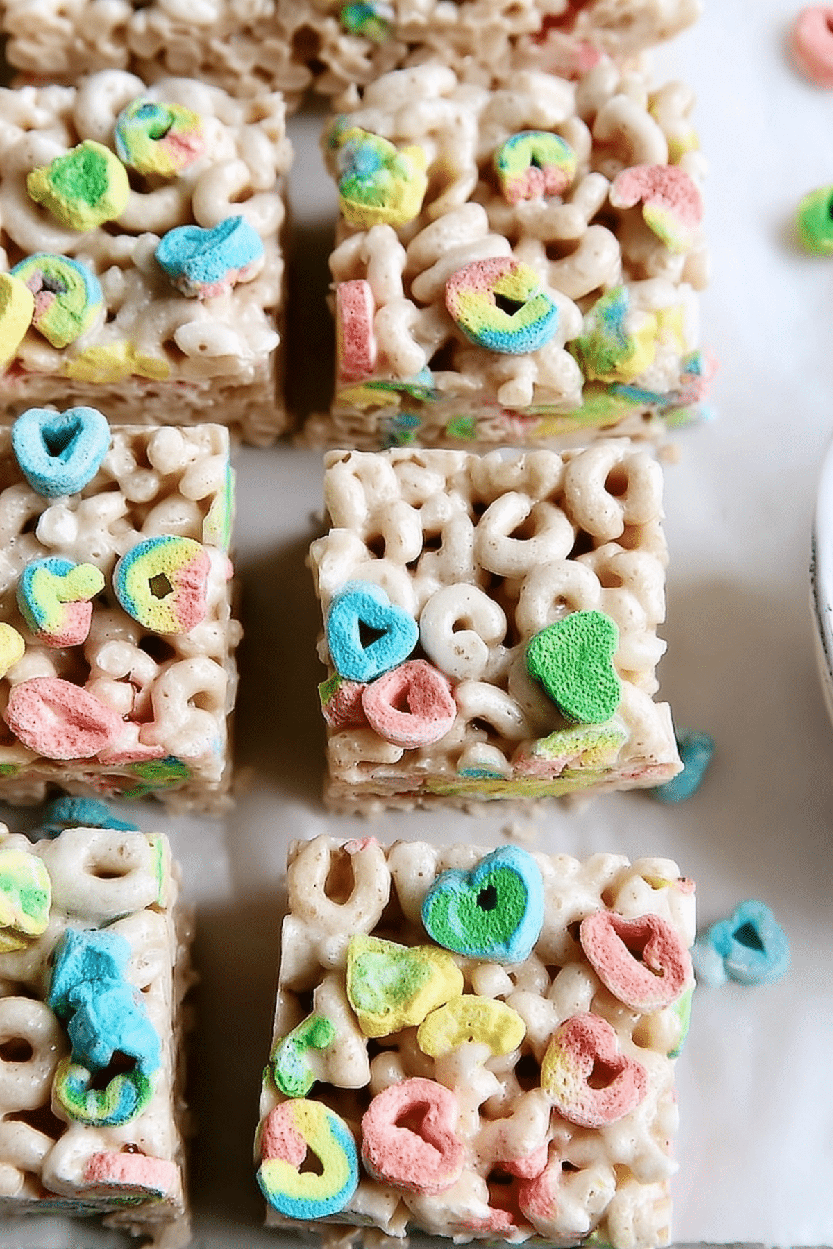 Lucky Charms Rice Krispie treats stacked on a plate with colorful marshmallows