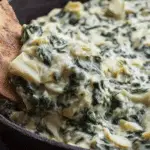 Healthy vegan spinach artichoke dip served with pita chips