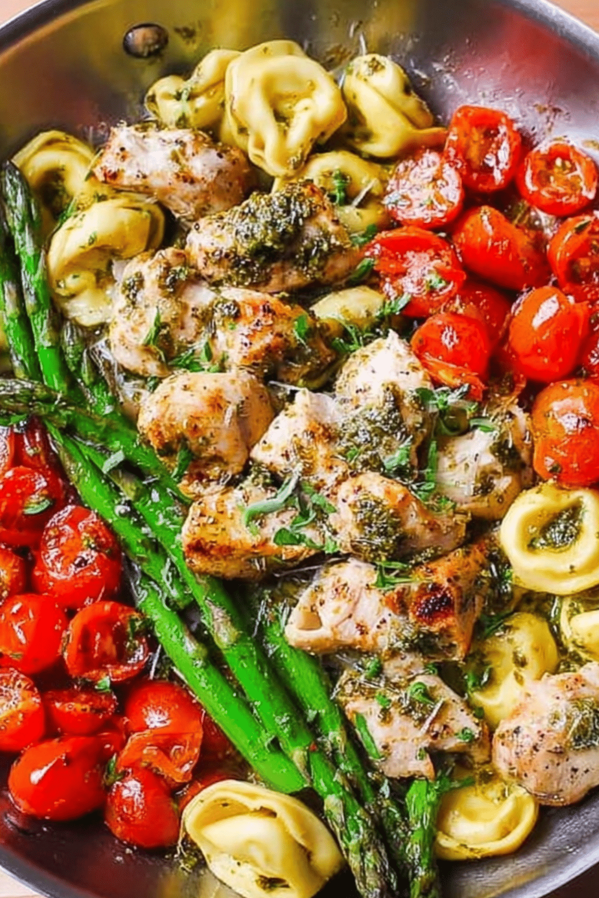 Pesto Chicken Tortellini and Veggies cooked in a skillet with asparagus and tomatoes