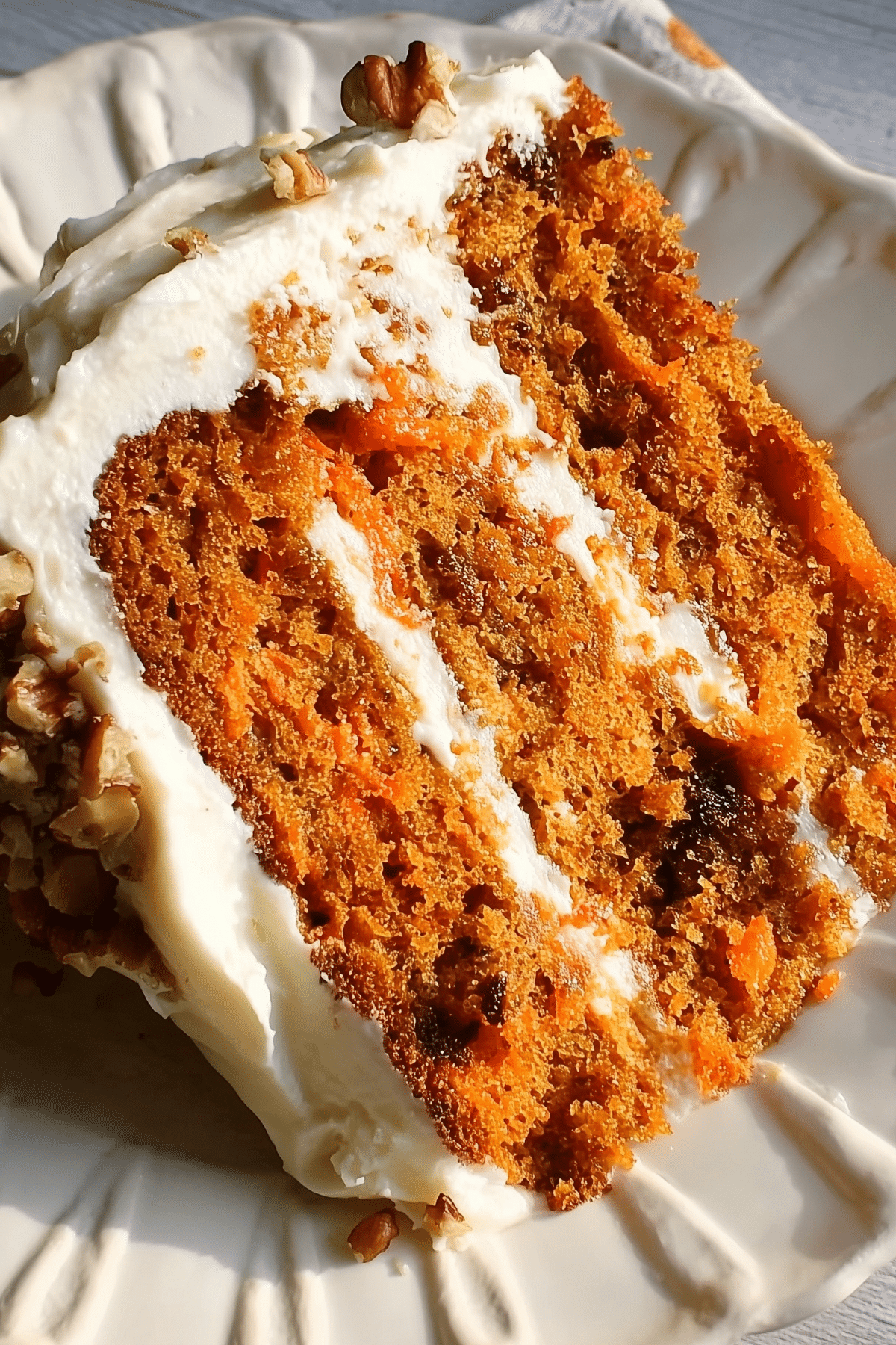Moist eggless carrot cake sliced and served with frosting