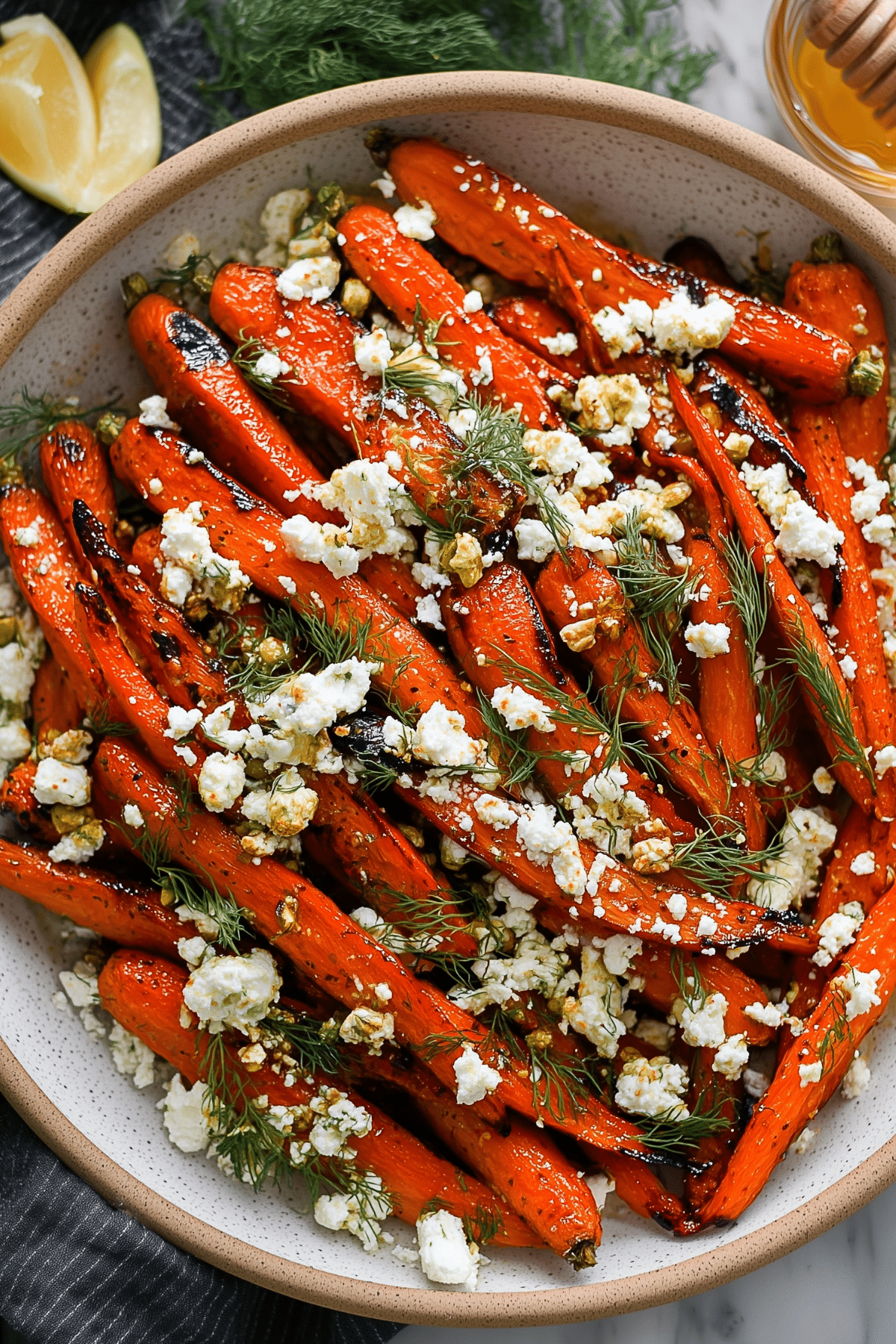 Honey Roasted Carrots with Feta & Dill served on a platter with fresh herbs and crumbled feta