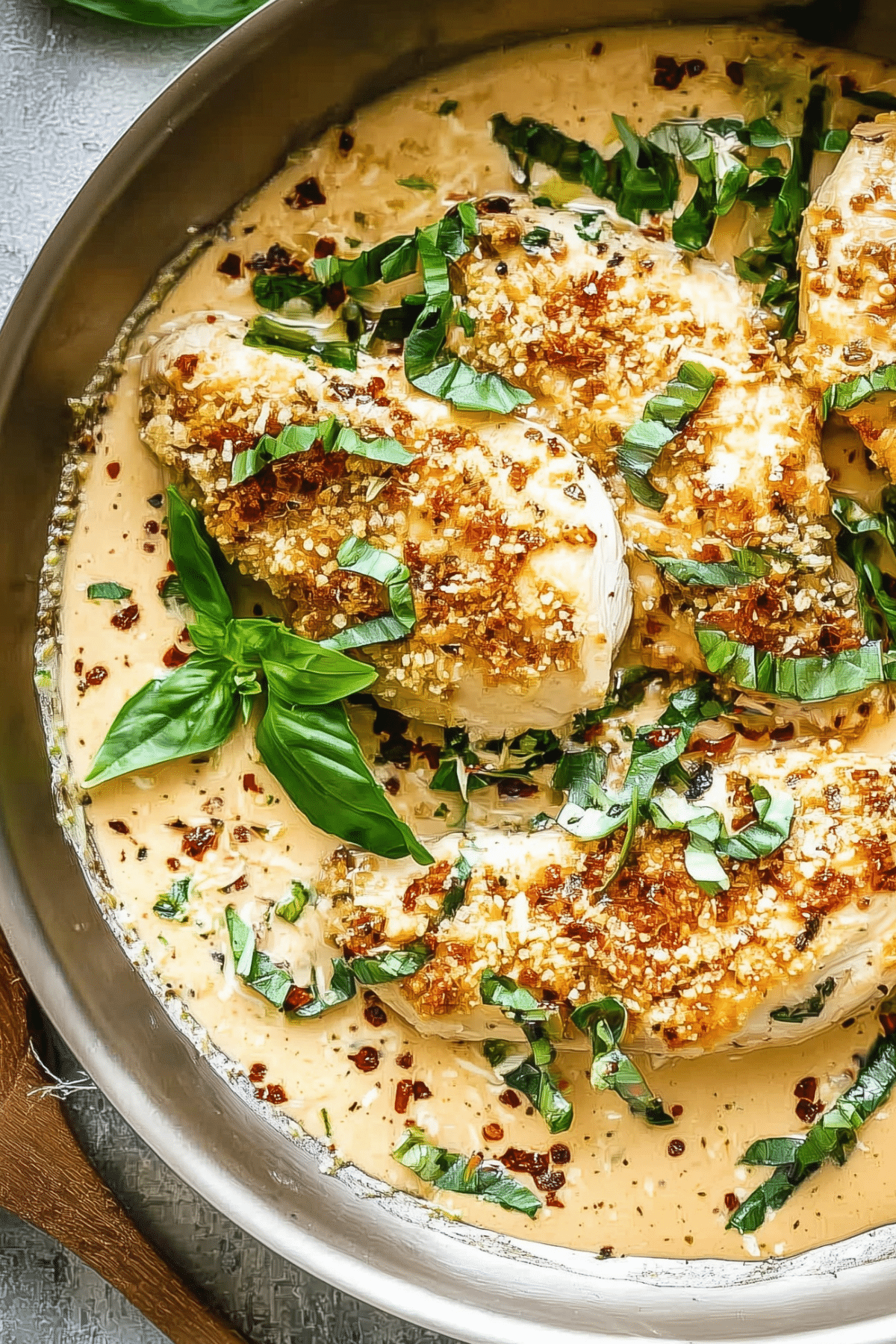creamy parmesan basil chicken in skillet with fresh basil
